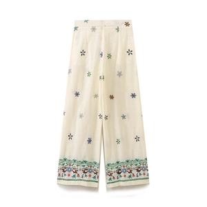 Detail der cremeweißen Weitbein-Hose aus Baumwollleinen mit bunter Blumenstickerei