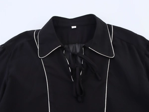 Detail of black chiffon blouse collar with white piping and bow tie neck closure