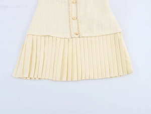 Détail d'une robe en tweed avec boutons métalliques, bords frangés et ourlet plissé