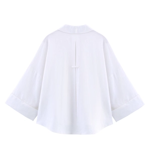 Detailed back view of white oversized shirt featuring box pleats and wide cuffs