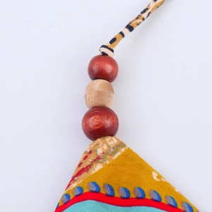 Close-up of decorative wooden beads and colorful tribal print fabric on neck strap