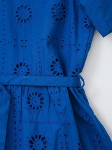 Detailed close-up of dark blue dress with intricate geometric embroidery and tie belt