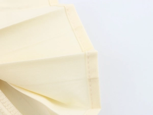 Gros plan sur le tissu plissé et les coutures d'une robe élégante de couleur beige