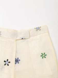 Detail der Blumenstickerei auf cremefarbener Baumwoll-Leinenhose mit Stoffstruktur