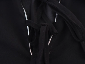 Detail of black long shirt with silver contrast stitching and adjustable ties