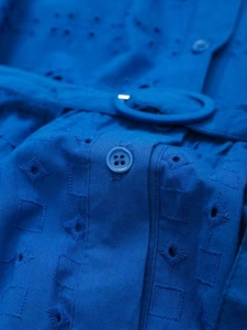 Close-up of blue dress with eyelet embroidery, fabric texture, buttons and belt detail