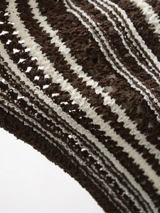 Close-up of brown and white striped crochet fabric with textured openwork knit details