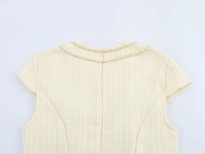 Détail de robe en tweed crème avec bordure à franges au col et fermeture éclair invisible