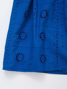 Detailed close-up of dark blue cotton fabric with intricate eyelet embroidery and stitching