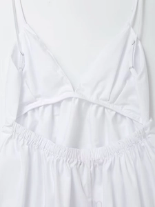 Detail of white backless dress featuring thin adjustable straps and elastic waist pleats