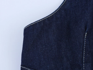 Détail du tissu en denim bleu foncé avec des coutures contrastées jaunes sur la robe