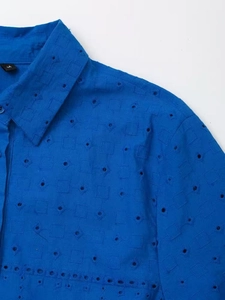 Detail of bright blue shirt showing intricate eyelet embroidery and M size label