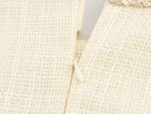 Détail du tissu en tweed crème avec fermeture éclair invisible et bordure en chaîne tressée