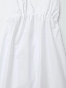 Detail of white deep V-neck dress featuring elasticated ruched waist and textured fabric