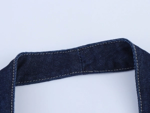 Détail des bretelles en jean bleu foncé avec double surpiqûre jaune sur la robe