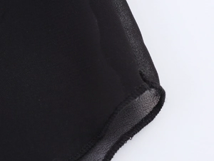 Close-up of black sheer fabric with fine stitching and lightweight texture detail