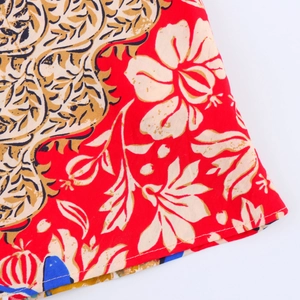Macro detail of red floral printed fabric with fine stitching and tropical patterns