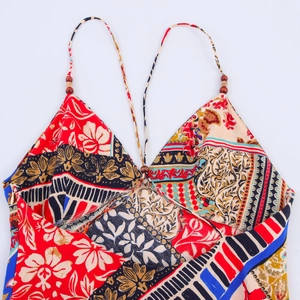 Detail of bohemian floral print dress with thin straps and decorative wooden beads