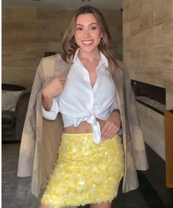 Detail of yellow sequin mini skirt with 3D texture paired with a grey textured blazer