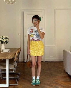 Detail view of a bright lemon yellow sequin mini skirt and printed white graphic t-shirt