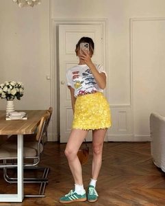 Detailed shot of bright yellow mini skirt with 3D sequin petals and floral texture