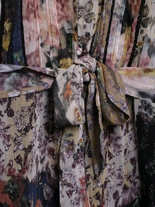 Détail d'une robe plissée à fleurs vintage avec fils dorés et ceinture à la taille