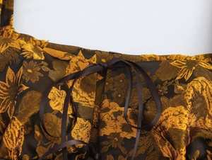 Detail of vintage jacquard fabric featuring dark brown gold floral patterns and satin ribbon