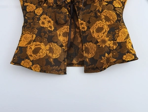 Close-up of golden floral jacquard fabric and brown ribbon lacing on a vintage summer corset