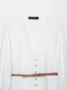 Détails de broderie et boutons nacrés sur une robe d'été blanche à manches longues
