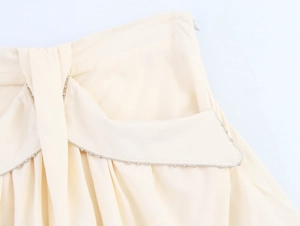 Close-up of cream A-line skirt waist with layered ruffle and pearl bead trim details