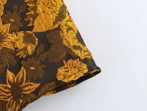 Detail of premium black and gold floral jacquard fabric with clean hemline stitching