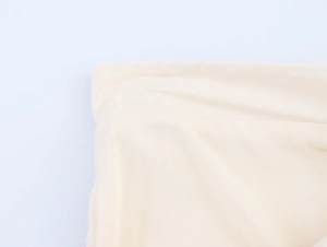 Detail of ruffle trim and woven texture on a beige French style A-line mini dress