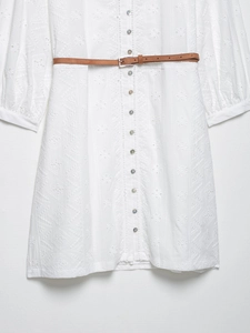Gros plan d'une robe blanche avec broderie géométrique et ceinture en cuir marron