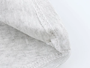 Macro detail of high-quality overlock stitching on heather gray knit cotton fabric