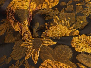 Close-up of premium black and gold jacquard fabric with detailed floral embroidery