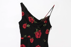 Close-up of asymmetrical draped neckline and red rose floral print on black slim dress