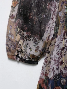 Détail d'une manche en mousseline fleurie avec rayures dorées et boutons recouverts
