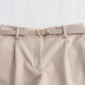 Detailed view of high-waisted beige cotton shorts with a matching belt and gold metal buckle