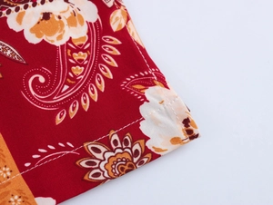 Close-up detail of paisley floral print on red fabric with precise white stitching quality