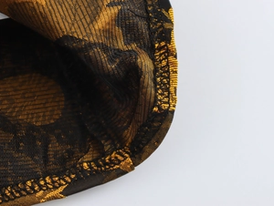 Detailed close-up showing black and gold jacquard fabric with double-needle hem stitching