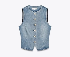 Détail d'un gilet en jean bleu clair délavé vintage avec des boutons dorés gaufrés