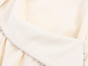 Detailed view of beige A-line dress featuring delicate silver beaded trim craftsmanship