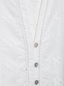 Détail de la broderie blanche et des boutons en nacre sur la robe chemise en coton chic