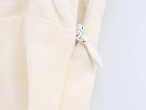Macro view of seamless invisible zipper detail on cream white French summer dress