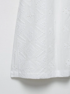 Gros plan d'une robe en coton blanc avec broderie anglaise et motifs géométriques fins