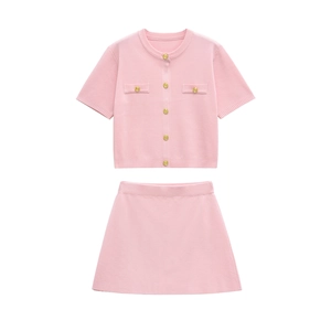 Detailed view of pink knitted two-piece set featuring golden embossed buttons on cardigan