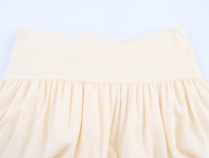 Detailed macro view of the ruched waistband and gathered fabric of the beige A-line skirt