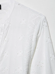 Détails d'un chemisier blanc avec broderie florale délicate et texture broderie anglaise