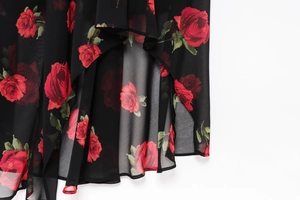 Detailed close-up of vibrant red rose floral print on lightweight black chiffon fabric