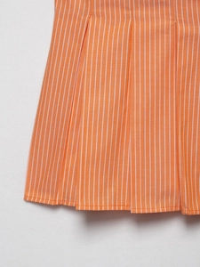 Detailed close-up of orange and white vertical stripes on pleated poplin cotton fabric